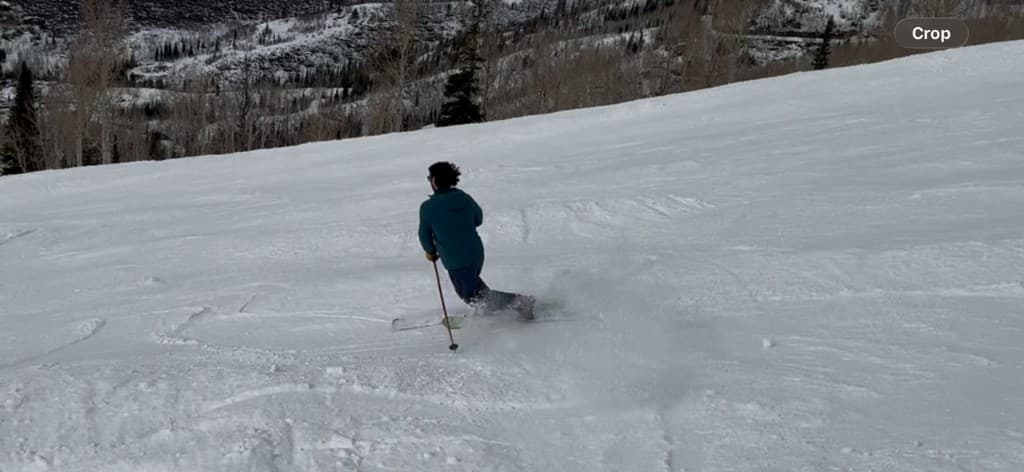 Dr. Beau Swann skiing down a snowy mountain slope, carving a turn with snow spraying behind him