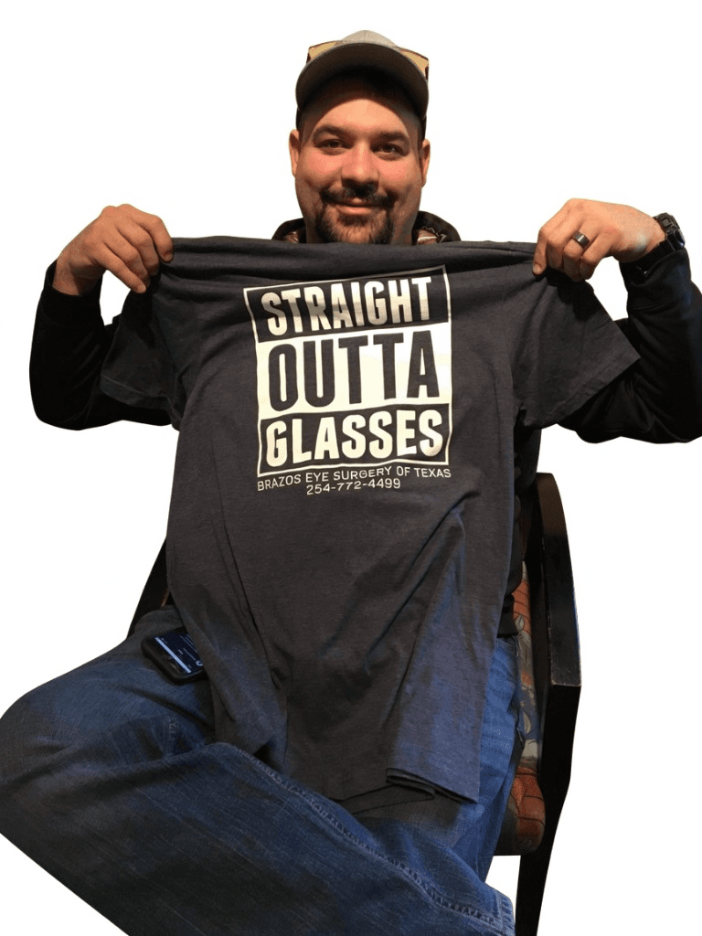 LASIK patient holding up a Straight Outta Glasses shirt